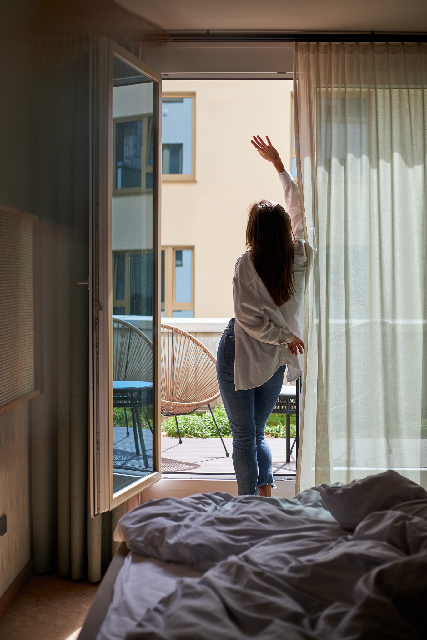 Eine Frau steht an einer offenen Balkontür in einem Zimmer im Cocoon Hotel am Sendlinger Tor